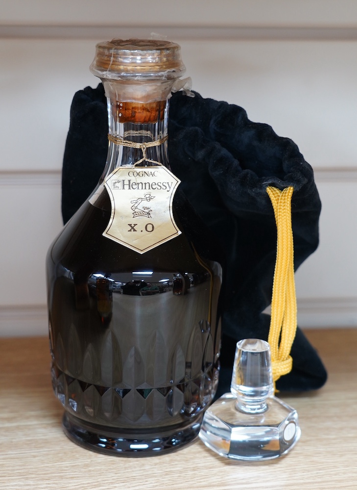 A bottle of Hennessy XO Cognac in a Baccarat crystal decanter, with separate glass stopper, contained with a drawstring bag. Condition - good